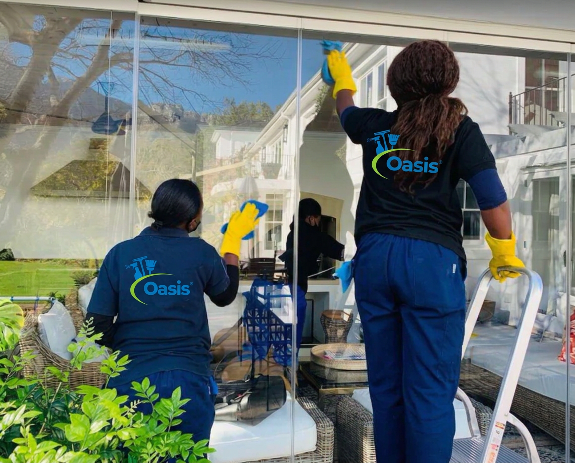 Oasis Cleaning team member cleaning a sunlit living room window